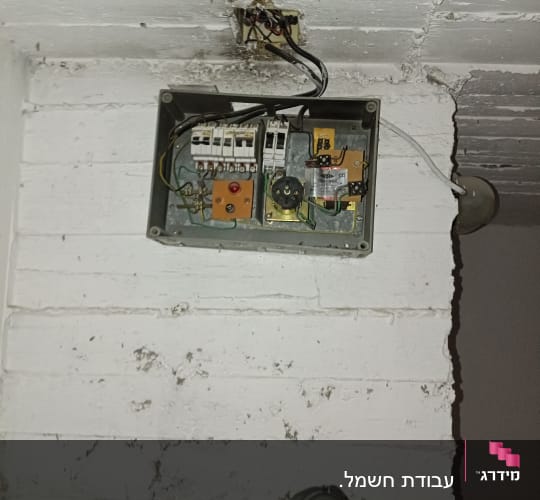תיבת חשמל פתוחה עם חוטים ומפסקים